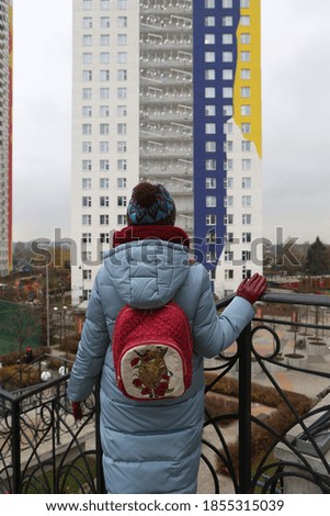 Russian woman with backpack. Architectural fashion, style. New building facade, house in housing complex ART, Avangardnaya Street, Krasnogorsk city, Moscow region, Russia. Moscow architecture landmark