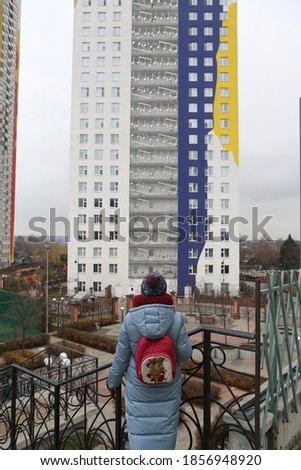 Russian woman with backpack. Architectural fashion, style. New building facade, house in housing complex ART, Avangardnaya Street, Krasnogorsk city, Moscow region, Russia. Moscow architecture landmark