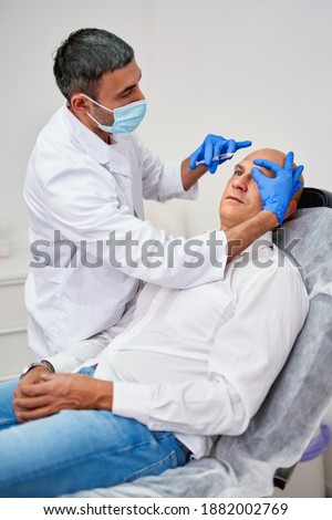 Cosmetic injection in the spa salon. Beautician makes injection into the patient's face. Beauty injections, mesotherapy, revitalization, cosmetic medicine injection - the concept of rejuvenation.