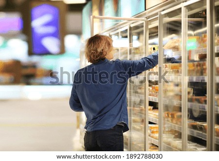 Man choosing frozen food from a supermarket freezer	