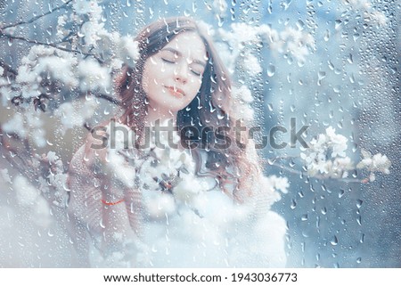 young girl spring portrait in a blooming garden, springtime happiness, rain weather in the park in April