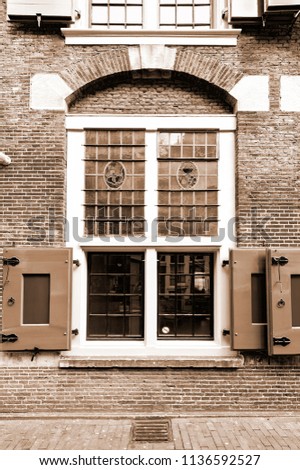Stained glass window of the traditional house in Amsterdam. Red brick facade of the old city house in Holland. Vintage Style Sepia photo