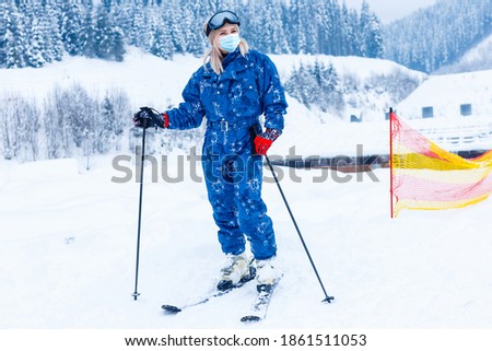 Retrato de una esquiadora con máscara médica durante el coronavirus COVID-19 en una montaña nevada en una estación de esquí