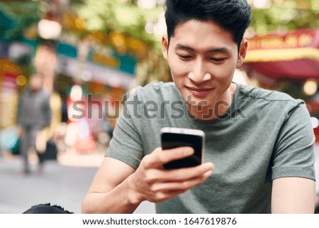 Young Vietnamese man using mobile phone in the city 