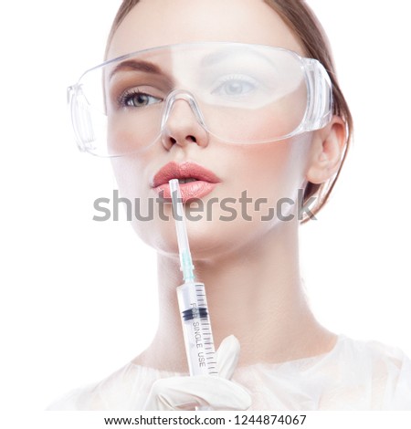 Close-up face of attractive woman doctor or beautician with syringe for injection, medical uniform. Isolated. White background. Health care concept 