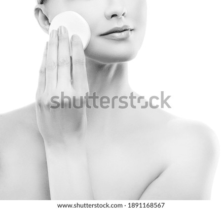 Partial portrait of beautiful young model woman beauty face with remove cosmetics with cotton pad, perfect skin, clean make-up. Monochrome