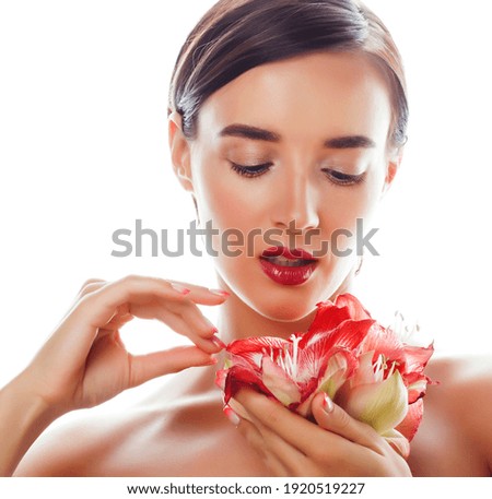 young pretty brunette real woman with red flower amaryllis close up isolated on white background. Fancy fashion makeup, bright lipstick, creative Ombre manicured nails