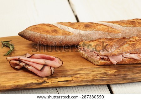 Ham sandwich with herb butter on a wood cutting board.