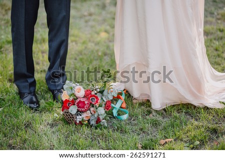 bridal bouquet style Bohemian on the green grass on a background of the bride and groom