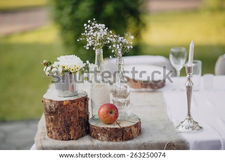 wild flowers in glass bottles and metal buckets on the festive table, wedding table