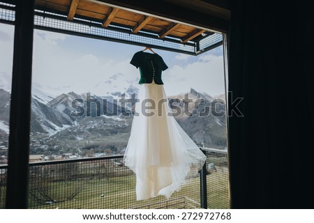 Vintage wedding dress hanging on a balcony on a background of snow-capped mountains
