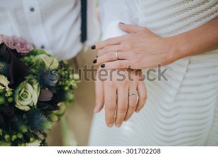 man in beige trousers and brown leather shoes and a girl in a white dress and shoes with bouquet holding hands