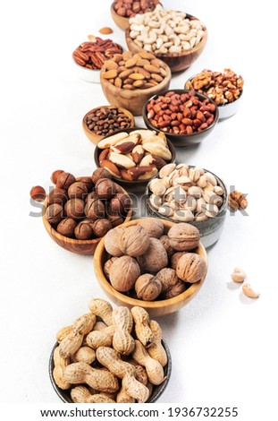 Assortment of nuts in bowls. Cashews, hazelnuts, walnuts, pistachios, pecans, pine nuts, peanuts, macadamia, almonds, brazil nuts. Food mix on white background, top view, copy space