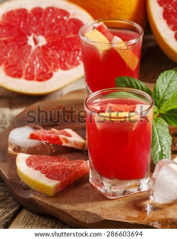 Fresh juice of red grapefruit pulp, ice and citrus slices, selective focus