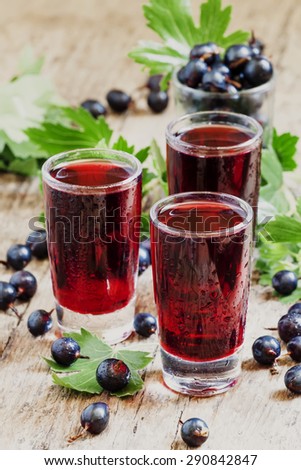 Fresh black currant juice with berries in glasses on an old wooden table, selective focus