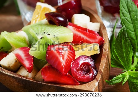 Dietary mixed fruit salad with fruit and berries in a wooden bowl, selective focus