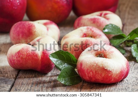 Flat Nectarines with leaves on the old wooden table, selective focus