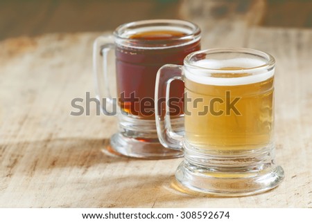 Light and dark beer in old-fashioned circles on old wooden table, selective focus