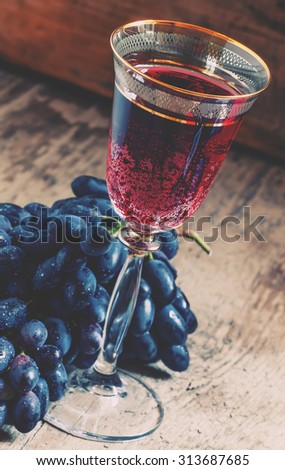 Red sparkling wine in the glass, blue grapes in the wine cellar, selective focus