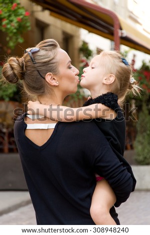 Mother and daughter kiss each other during a walk in the city