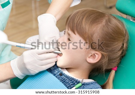 little girl on reception at the dentist. sitting in a chair and treats teeth