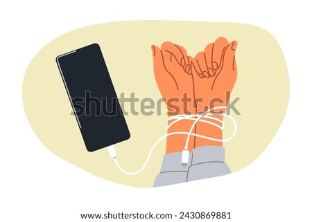 Hands digital hostage are tied with headphones from mobile phone, and symbolize dependence on social networks. Person has become digital hostage due to uncontrolled visits to websites and applications