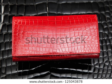 Red crocodile leather wallet laying on black leather