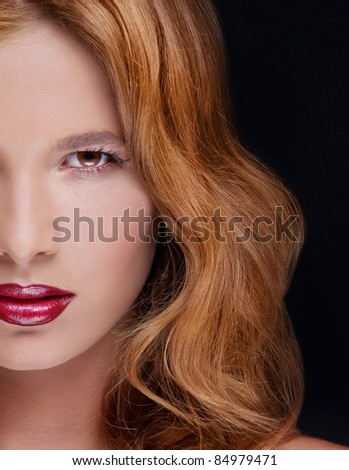 Attractive young woman with red lips and brown eyes looking to the camera on black background, caucasian woman makeup