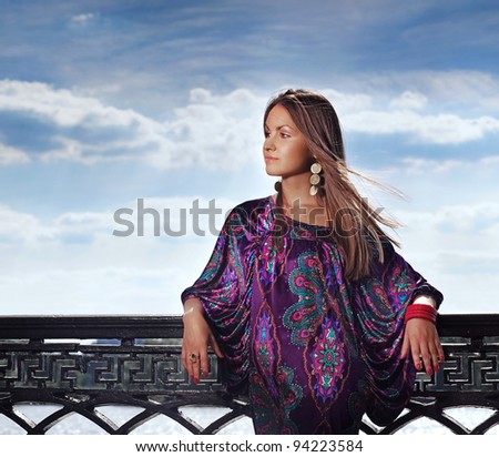 Attractive young woman in violet dress looking out the camera near the river in sunny day