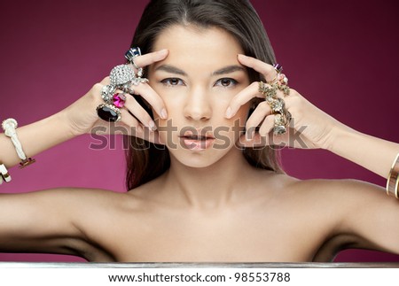 Attractive young woman with diamonds on the hands looking to the camera on the red background