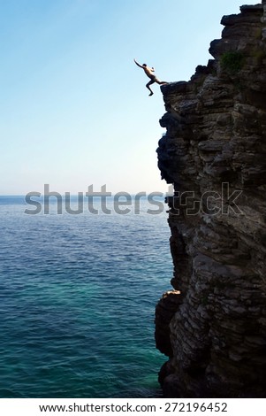 man jumps from a high cliff into the sea