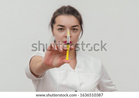 doctor woman with black hair holds a medical syringe in front of her. Face out of focus