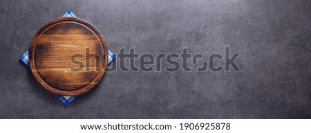 Pizza cutting board and cloth napkin on stone surface of table. Food recipe concept at tabletop or wall background texture with copy space. Flat lay of  panorama, panoramic top view