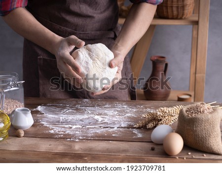 Baker man kneading dough and bakery ingredients for homemade bread cooking on table. Bakery concept near wall background texture