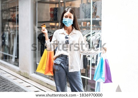 Portrait of Asian girl excited beautiful girl wearing protective mask happy smiling with holding credit card and shopping bags enjoying in shopping relaxed expression, lifestyle concept.