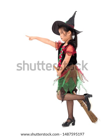 Little girl asian in witch costume, her hand is holding the broom while standing and pointing to the front. Halloween concept.