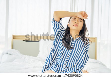 Beautiful Asian women touch head suffering from migraine or headache and feel strain and serious on bed, bad news