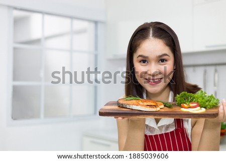 Asian woman holding a tray of salmon steak.