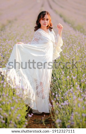 Blond long haired woman in lavender field. Style life enjoying journey to travel on vacation with relaxation with in long white dress outdoors on summer day.