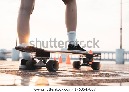 Asian woman leg on surf skate or skate board in outdoor Park at sunset. sport training for trendy people.