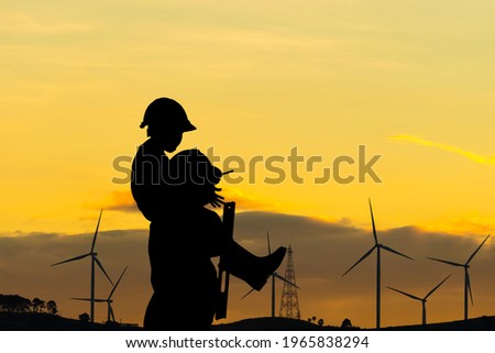 Silhouette of father and son with clipping path in hard hat, Happy dad carrying son on shoulders checking project at wind farm site on sunset in evening time
