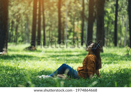 A beautiful young asian woman enjoy listening to music with headphone with feeling happy and relaxed in the park