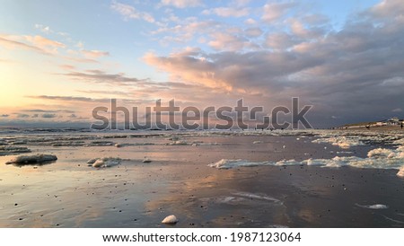 La glace dérive sur la plage sous le ciel nuageux au coucher du soleil