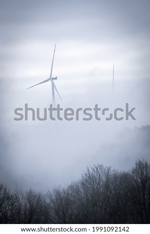 Un molino de viento en un bosque nublado