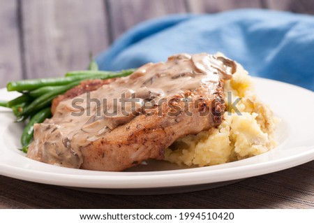 A crispy pork chop, mushroom sauce and creamy mashed potatoes