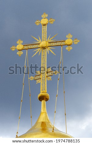 A cross on the dome of Trinity Cathedral against a cloud sky. Holy Trinity St. Sergius Lavra, Sergiev Posad. Moscow region, Russia