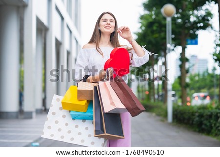 A young woman walking in the city with many shopping bags