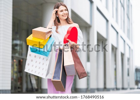 A young woman walking in the city with many shopping bags