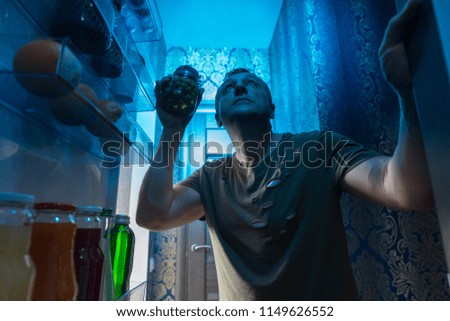 A man looking for food in the fridge in the darkness