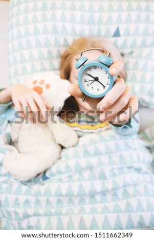 alarm clock disturbing a sleeping little girl that is defocused